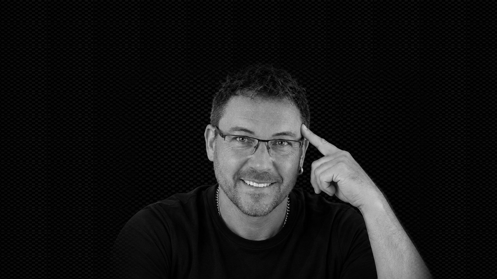 Alex lächelt in die Kamera und tippt sich an die Schläfe